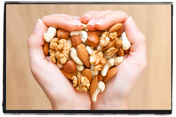 Hands cupped holding a mixture of nuts in a heart shape